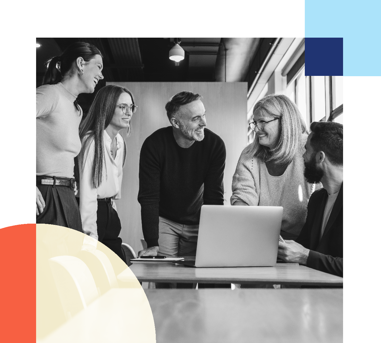 A group of people gathered around a laptop in an office